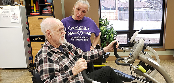 A staff member working with a resident on a therapy bike.